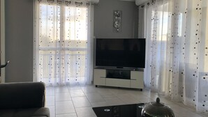 Una sala de estar con un sofá, un televisor sobre un mueble bajo y un tazón decorativo sobre una mesa.