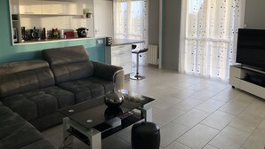 Una sala de estar moderna con un sofá, una mesa de centro de vidrio y un televisor.