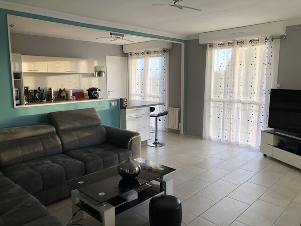 A modern living room with a sofa, a glass coffee table, and a TV.