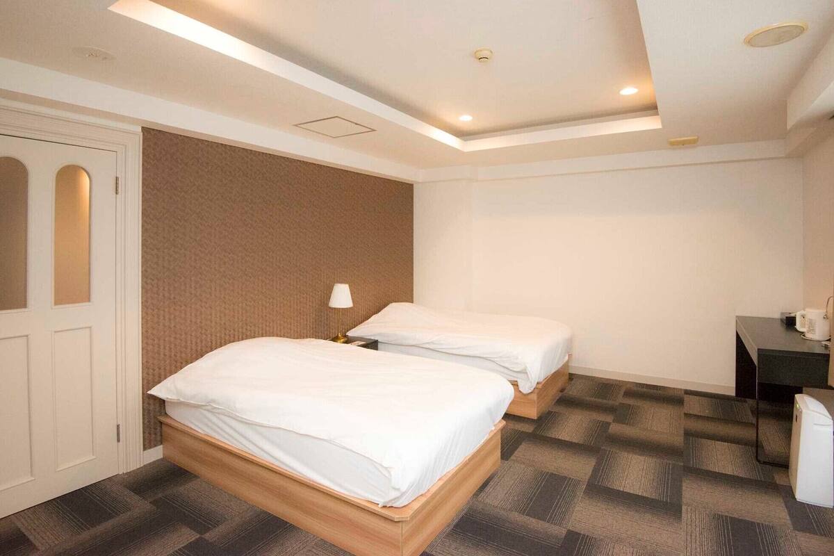 Habitación de hotel con dos camas, un escritorio y una silla.