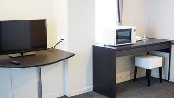A hotel room with a flat-screen TV, a microwave, a desk, and a chair.