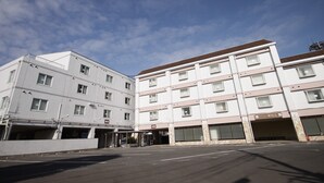 Ett hotell med flera våningar och modern design, med en ingång som är skyddad från väder och vind samt ett flertal parkeringsplatser.