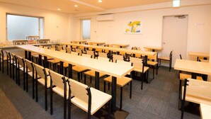 Ett konferensrum med långa bord och stolar, ett litet pentry och en dörr med en skylt.