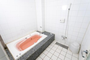 A bathroom with a rectangular bathtub, a shower area, and a toilet.