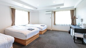 Ett hotellrum med två sängar, ett skrivbord med en stol och en luftkonditioneringsanläggning.