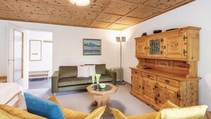 Ein gemütliches Wohnzimmer mit Holzboden, einem grünen Sofa, einem gelben Sessel und einem Holzschrank.