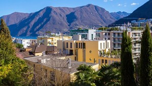 Une ville côtière dotée de bâtiments modernes, avec une chaîne de montagnes en arrière-plan et des balcons bien visibles.