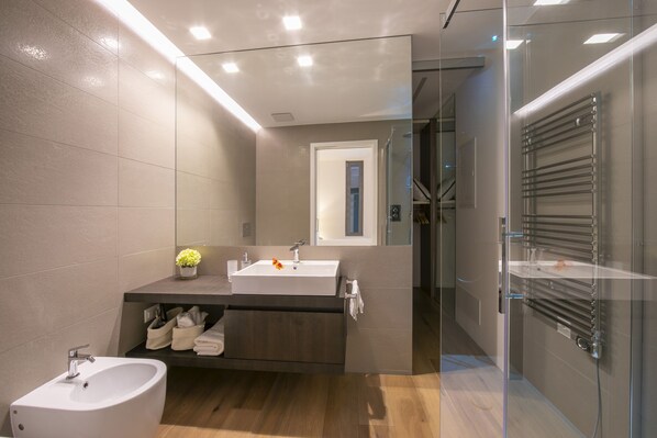 A modern bathroom with a large sink, mirror, and shower area.