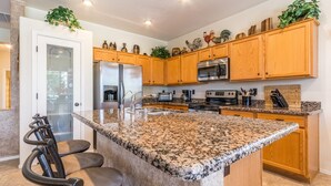 Eine Küche mit Granit Arbeitsplatten, Holzschränken, Edelstahlgeräten und einer Bar mit Hockern.