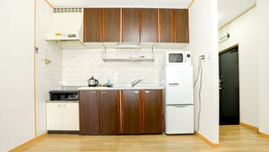 A compact kitchen with wooden cabinets, a white refrigerator, and a microwave. - Nipponbashi Super House (Moriguchi)