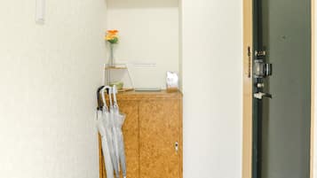 A small, enclosed room with a wooden cabinet, a door, and a marble floor.