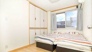 A bedroom with a bed, a wardrobe, and a window with curtains. - Nipponbashi Super House (Moriguchi)