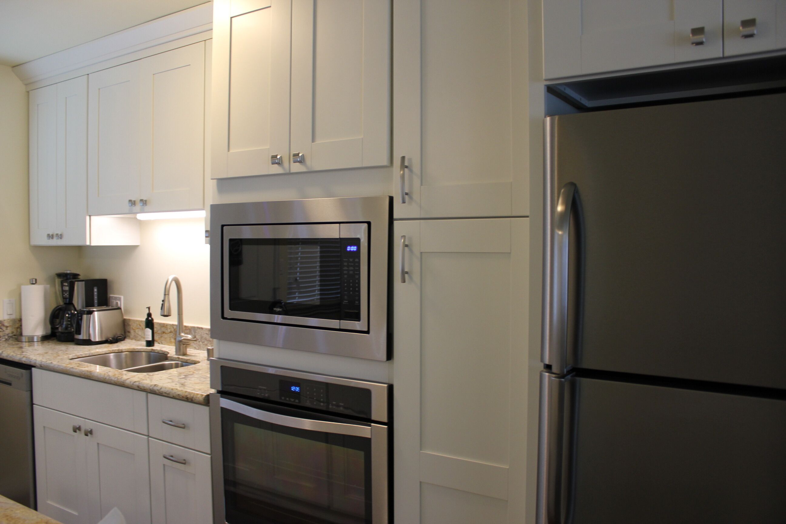 A modern kitchen with stainless steel appliances, white cabinetry, and a built-in microwave.