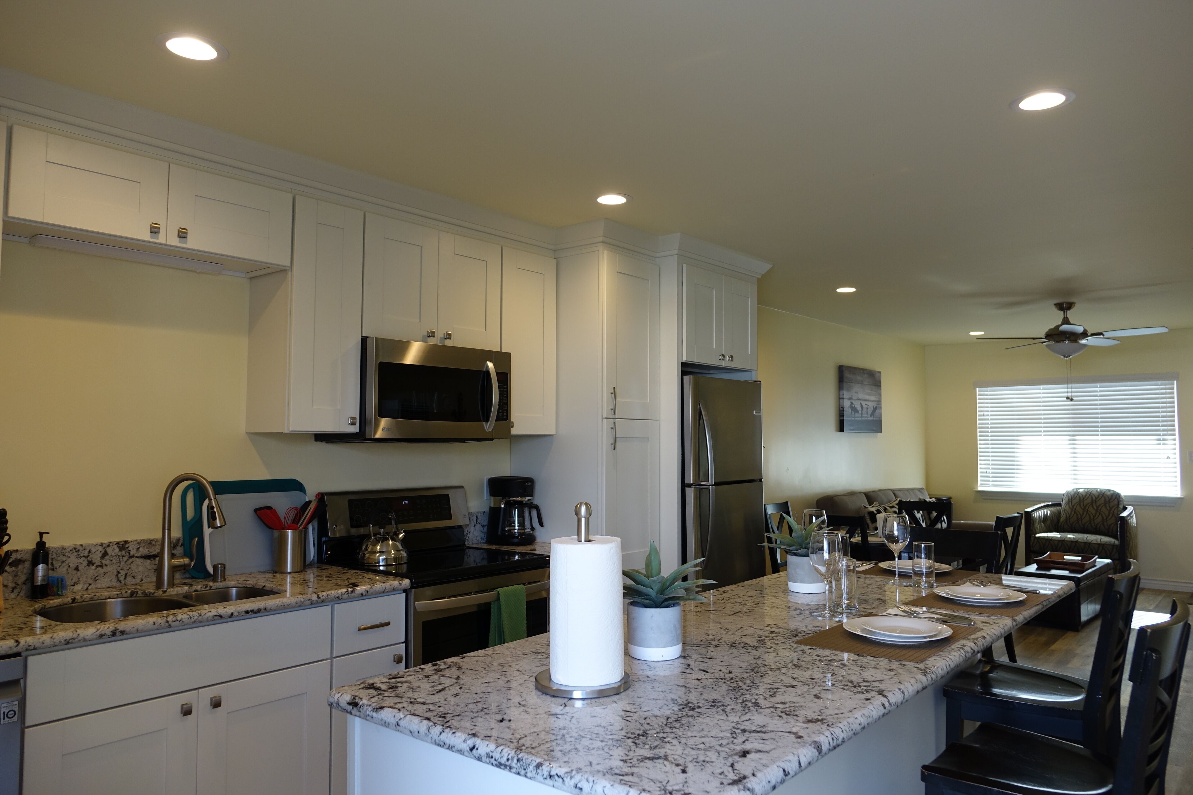 A modern kitchen with white cabinets, stainless steel appliances, and a marble countertop.