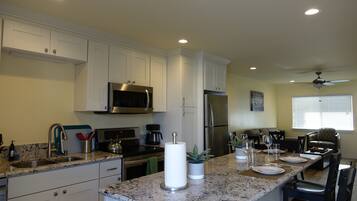 A modern kitchen with white cabinets, stainless steel appliances, and a marble countertop.