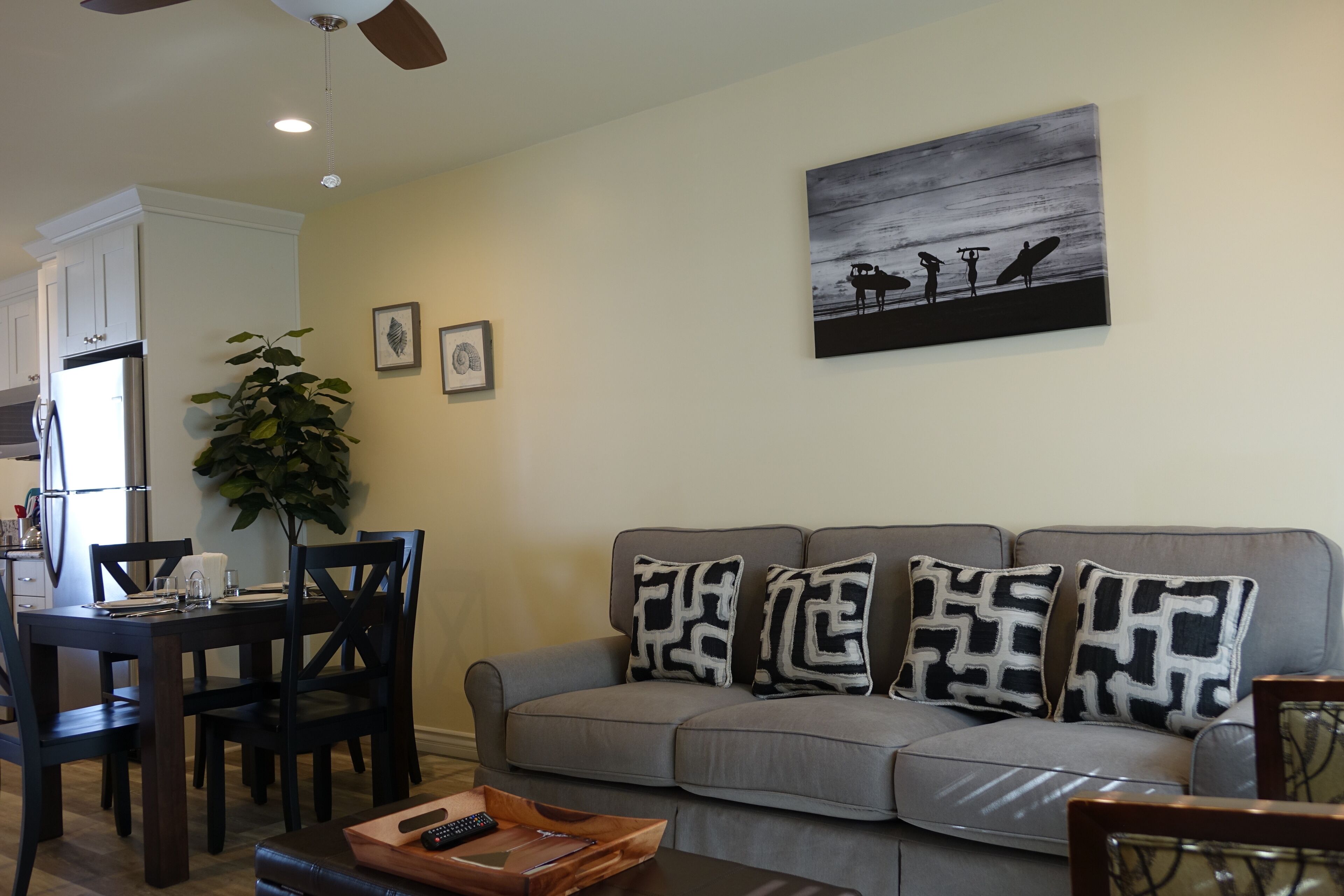 A living room with a grey sofa, a wooden coffee table, and a dining area with a dark wooden table and chairs.