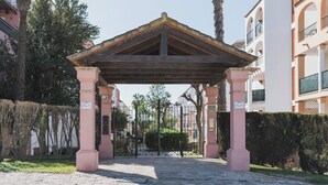 A covered outdoor area with a wooden roof, pink pillars, and a gated entrance. - Apartamento Cóncavos  (Zahara de los Atunes)