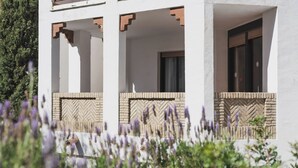 A building with three balconies, each with a stone base and a white wall above. - Apartamento Cóncavos  (Zahara de los Atunes)