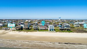 A coastal residential area with houses near the beach, a water tower, and a sign indicating beach access.