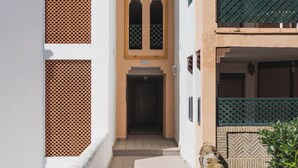 Un estrecho callejón con una entrada de azulejos que conduce a un edificio de fachada color beige y un balcón verde.