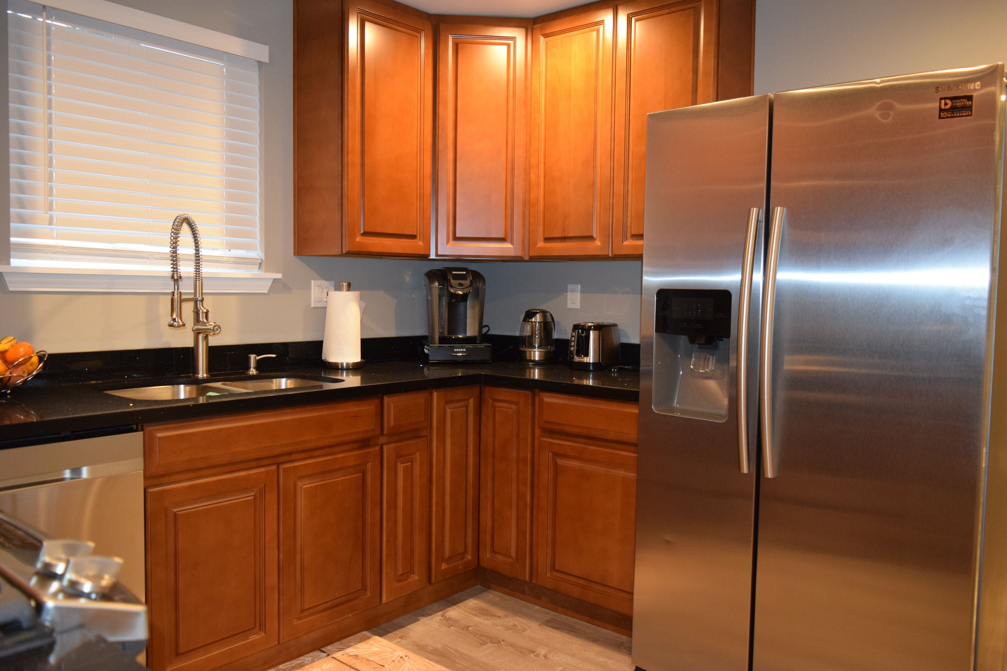 A modern kitchen with wooden cabinets, a stainless steel refrigerator, and a coffee maker.