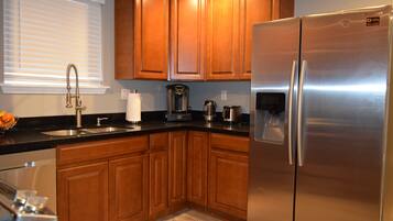 A modern kitchen with wooden cabinets, a stainless steel refrigerator, and a coffee maker.