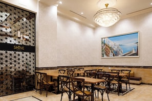 Un comedor con una mesa larga y varias sillas, un muro decorativo con un diseño geométrico y una araña.