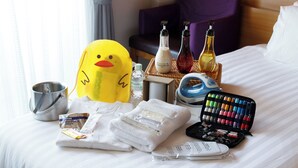 A neatly made bed with a variety of toiletries, including a yellow rubber duck, a bottle of conditioner, and a makeup palette. - FIVE HOTEL OSAKA (Osaka)
