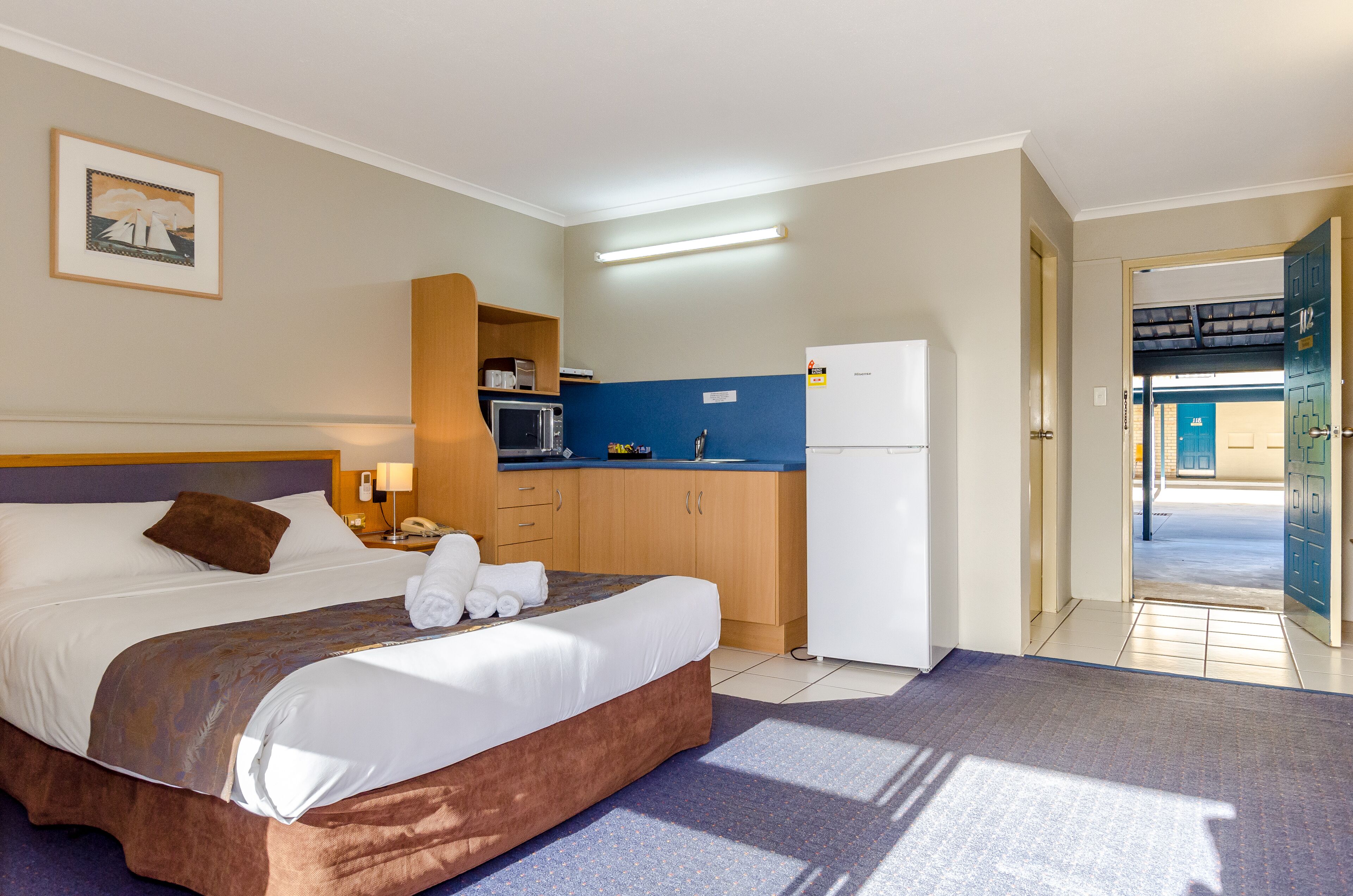 Ein Hotelzimmer mit Bett, Schreibtisch, Mikrowelle, Kühlschrank und Blick ins Freie.