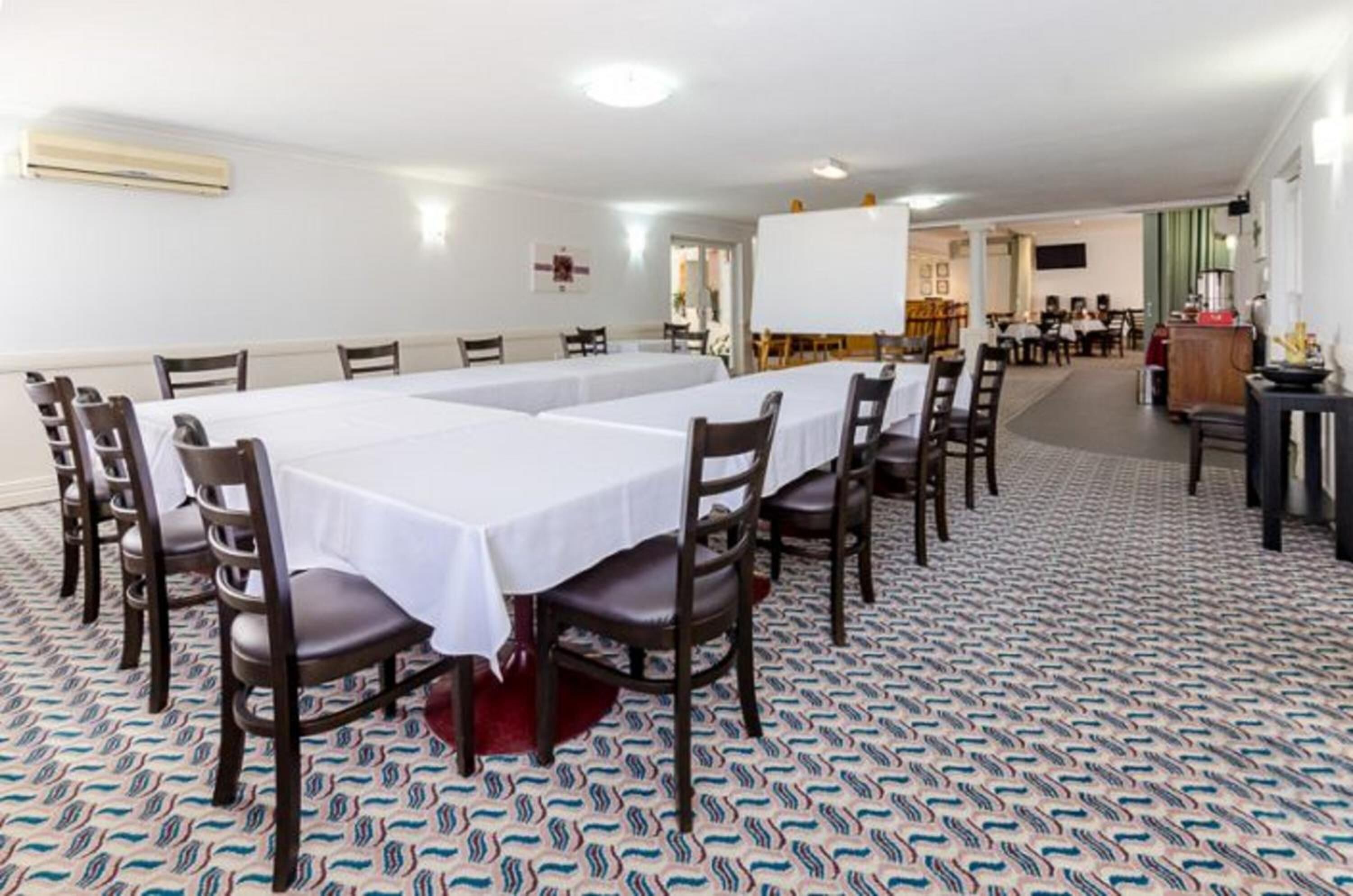 Una sala de conferencias con una larga mesa, varias sillas y una alfombra estampada.