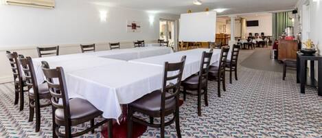 Una sala de conferencias con una larga mesa, varias sillas y una alfombra estampada.
