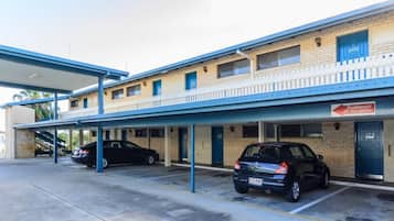A motel with a covered parking area and two cars parked inside.