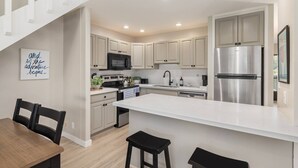 Una cucina moderna con mobili chiari, elettrodomestici in acciaio inossidabile e un'isola grande.