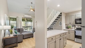 Una cucina moderna con forno integrato, microonde e piano cottura. Una scala conduce a un livello superiore.