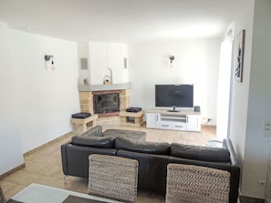 A living room with a fireplace, a TV, a sofa, and two armchairs.