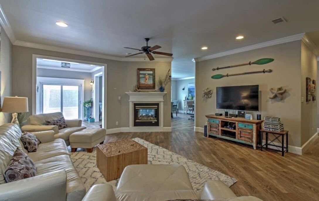 A spacious living room with a fireplace, a television, and a ceiling fan.