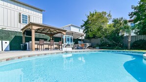 A swimming pool with a covered patio area, a wooden fence, and a house in the background. - 6 BR, Huge Pool/Jacuzzi, Movie Theater, Luxurious Yard, Discounted Golf Cart (Destin)