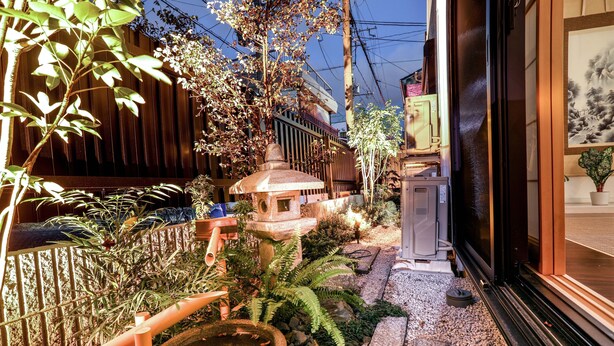 A narrow pathway with a stone fountain, a small pagoda, and a wooden fence. - Summer Lotus House Osaka (Osaka)