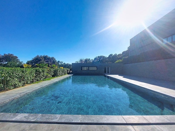 A clear swimming pool with a modern building in the background.