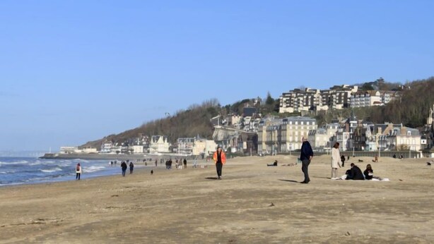A beach with people walking and sitting, buildings in the background, and a clear sky. - Apartment Carnot by Interhome (Deauville-Trouville)