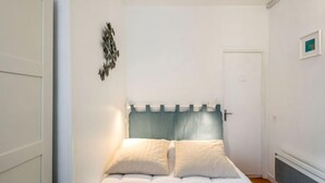 A bedroom with a bed, a door, and a wall-mounted light fixture. - Apartment Carnot by Interhome (Deauville-Trouville)