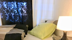A hotel room with a bed, pillows, a lamp, and a window with curtains.