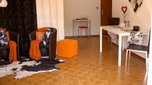 A living room with a sofa, ottoman, and a table with a coffee cup.