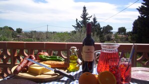 A table with food and drinks, a bottle of wine, and a scenic view in the background. - Studio apartment on rural smallholding, 3km from beaches and amenities (L'Ampolla)