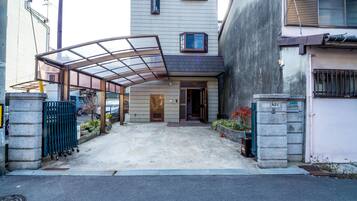 A building with a covered entrance, a gated driveway, and a small garden area.