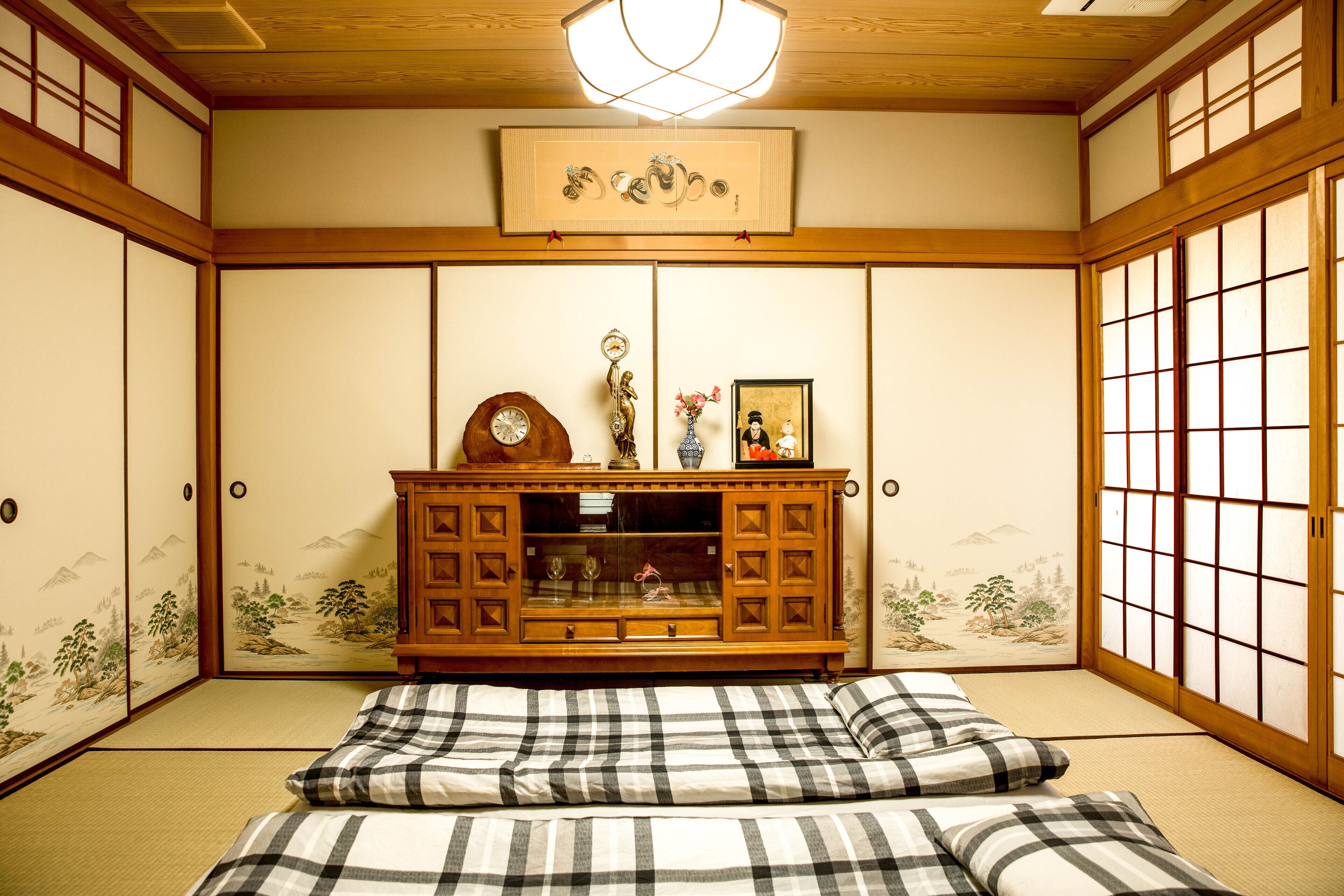 Une pièce de style japonais traditionnel, avec un sol recouvert de tatamis, un meuble bas en bois doté de portes en verre et une porte coulissante de type shoji.