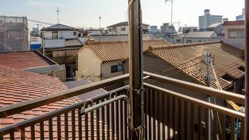 A balcony with a metal railing overlooking a residential area with tiled roofs.