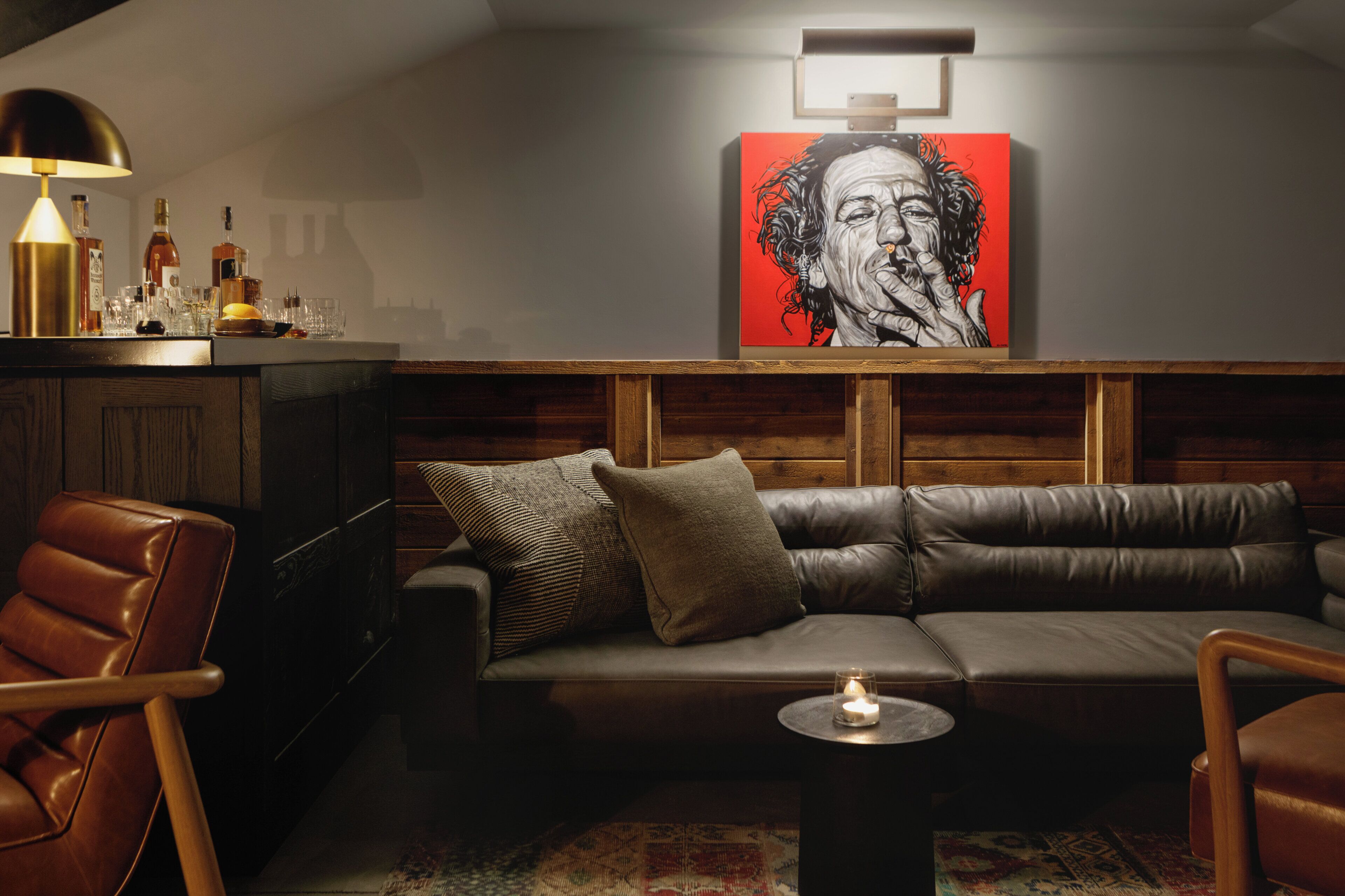 A modern living room with a leather sofa, a coffee table, and a wall-mounted painting.