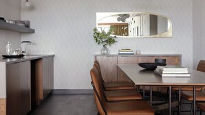 A modern dining area with a wooden table, leather chairs, a mirror, and a vase with greenery. - Kimpton Armory Hotel Bozeman by IHG (Bozeman)