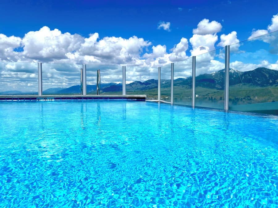 A clear blue pool with a view of mountains and a cloudy sky.